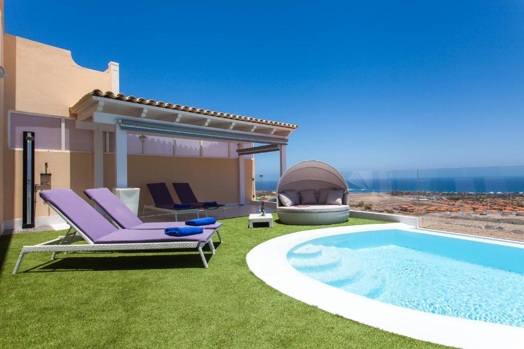 visualización de un patio trasero con piscina y casa en Suite Golf Caleta Abril, en Caleta de Fuste