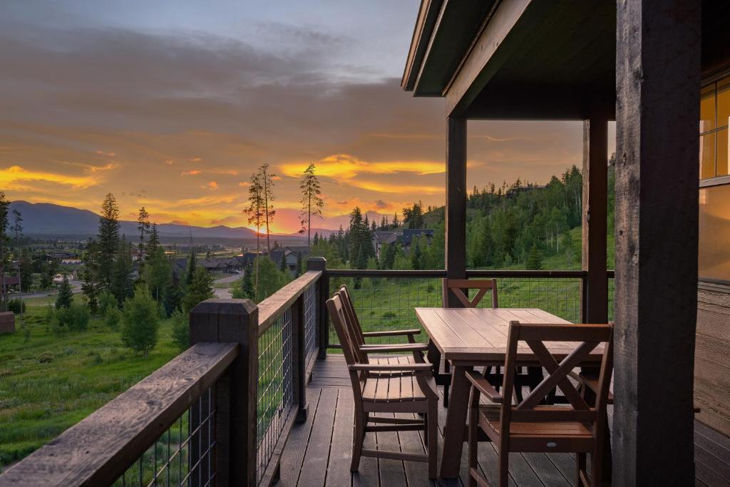 a wooden table and chairs on a porch with a sunset at Aspen View Chalet home in Fraser