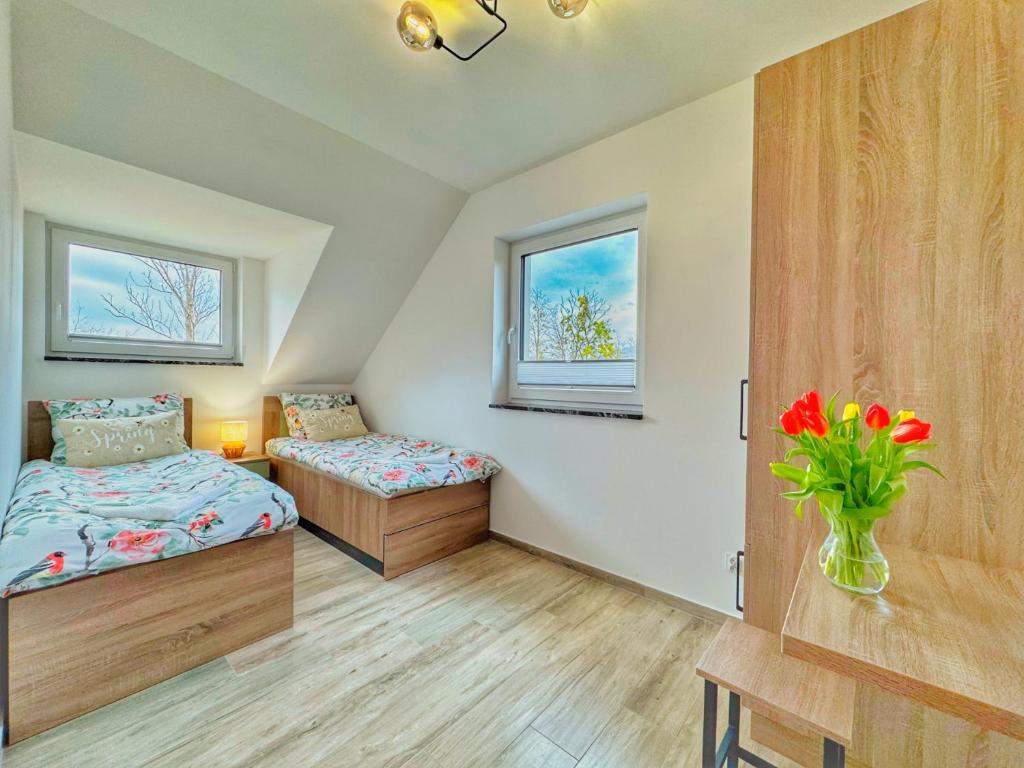 a bedroom with two beds and a vase of flowers at Miodomki in Brenna