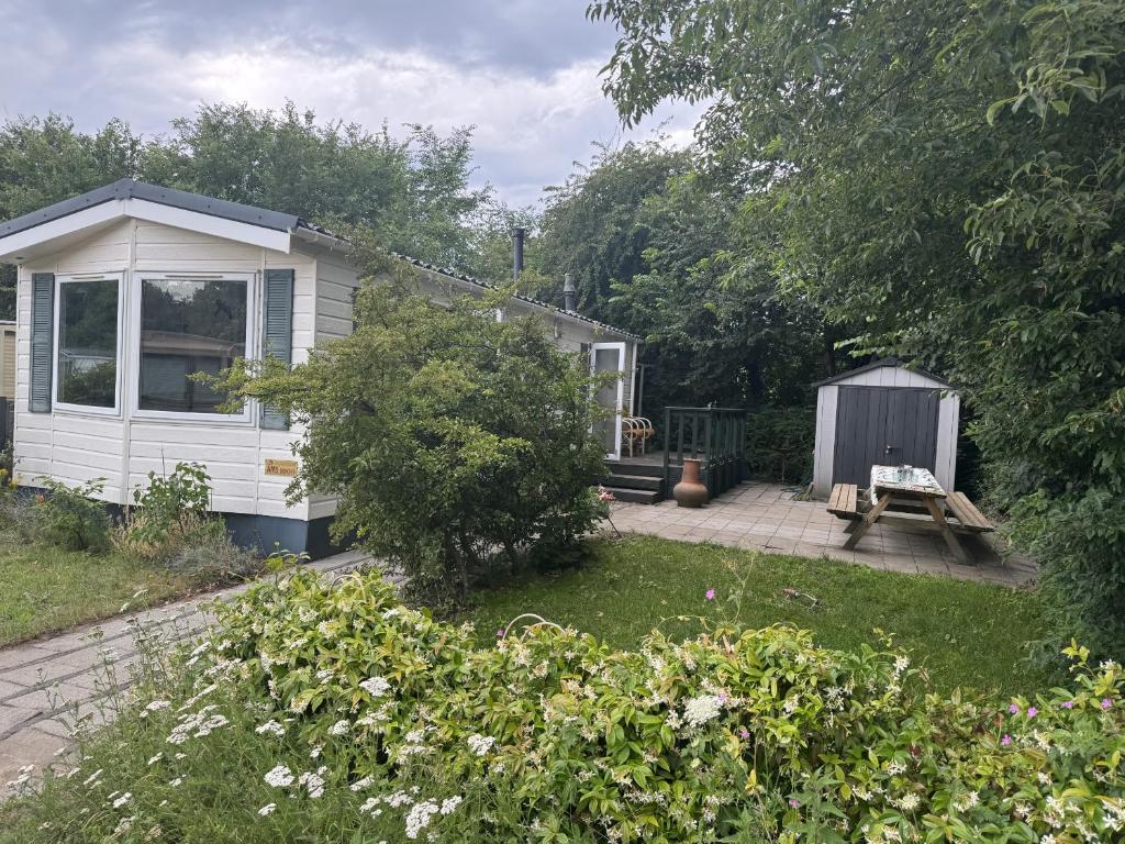 a small white house with a picnic table in a yard at KD 743 - Vakantiepark Kijkduin in The Hague