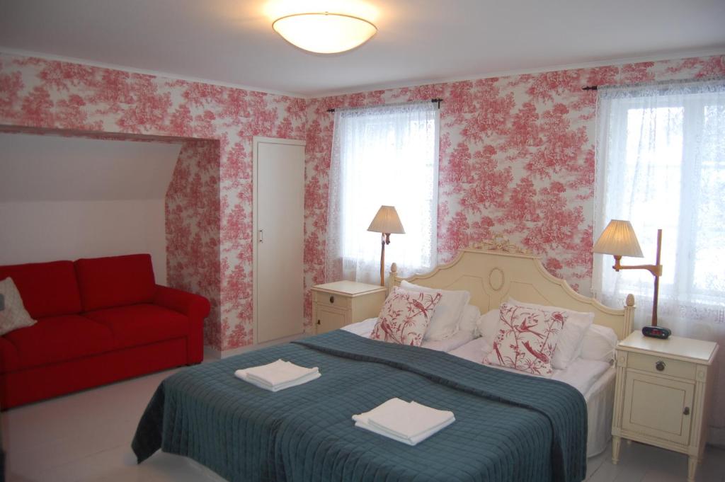 a bedroom with a bed and a red couch at STF Vickleby Bo Pensionat in Färjestaden