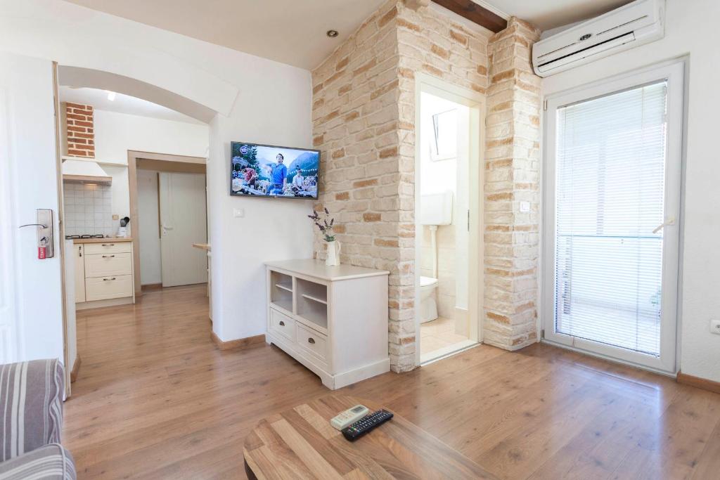 a living room with a tv on a brick wall at Apartments Sanja in Makarska