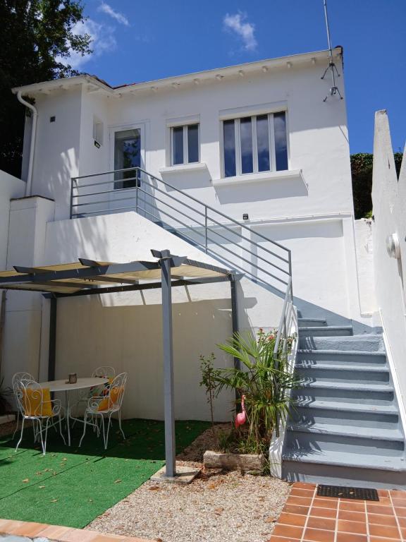 une maison blanche avec des escaliers, une table et des chaises dans l'établissement Petite maison avec jardin, à Royan