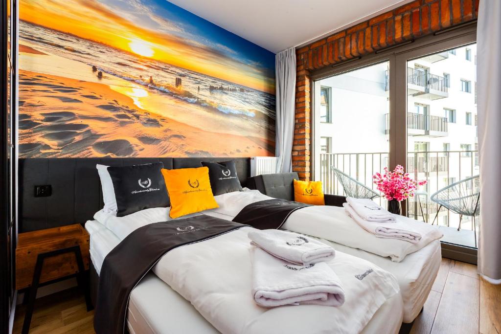 グダニスクにあるApartamentyGdansk eu - ŻURAWIE II - IIの壁に絵が飾られた部屋にベッドが2つある