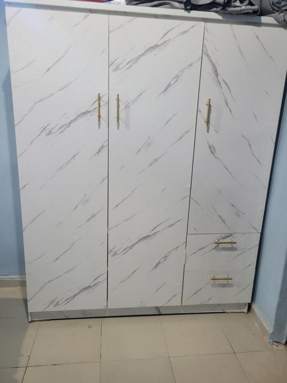 Benin CityにあるBellevette homeの金色の取っ手が付いた4つの扉が付いた白いキャビネット