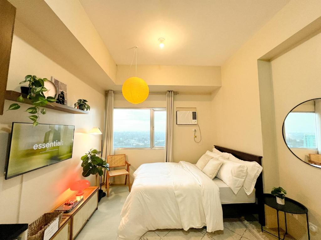 a bedroom with a white bed and a large window at Avida Towers - Noma CDO in Cagayan de Oro