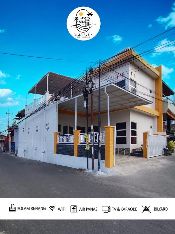 a white building with yellow trim on a street at Villa Putih O3 in Batu