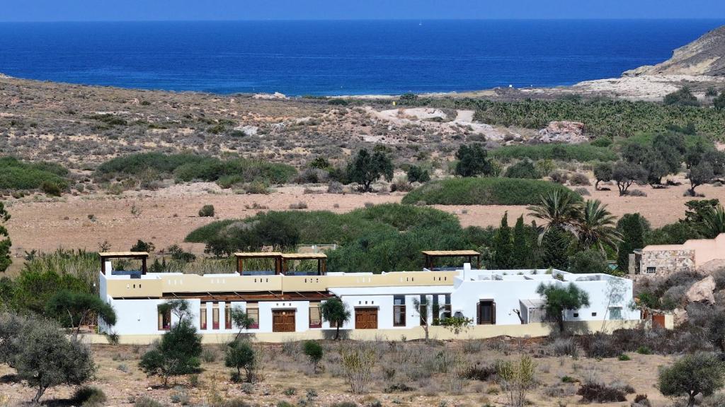 a white house in the desert with the ocean in the background at Hotel Los Patios - Parque Natural in Rodalquilar