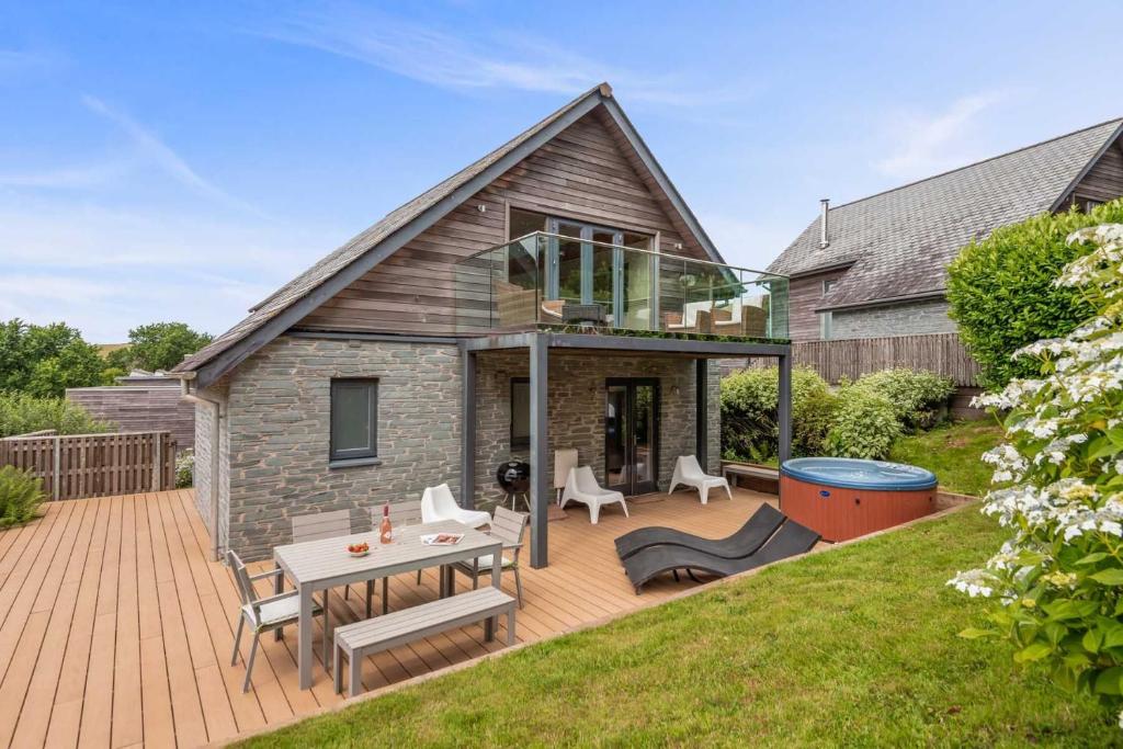 a house with a deck with a table and chairs at House 32 in Looe