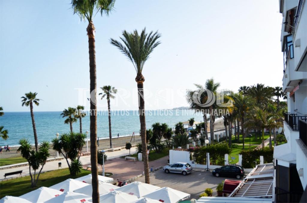 a view of the beach and palm trees from a building at Terrasol Pirámides Puerto Blanco in Caleta De Velez