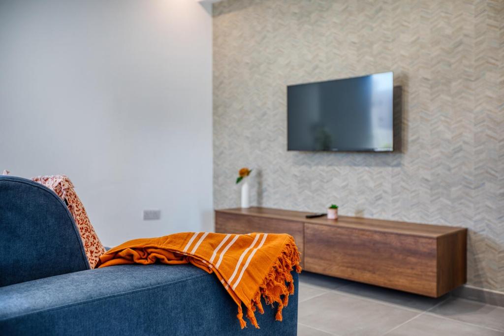 a living room with a blue couch and a tv at Cozy Apartment Heart of St Julians Sleeps 5 in San Pawl il Bahar