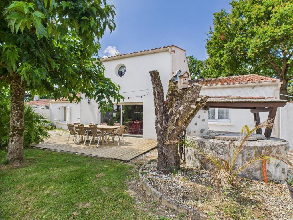a white house with a wooden deck with a table and chairs at Belle et spacieuse maison au calme pour 8 in Saint-Révérend