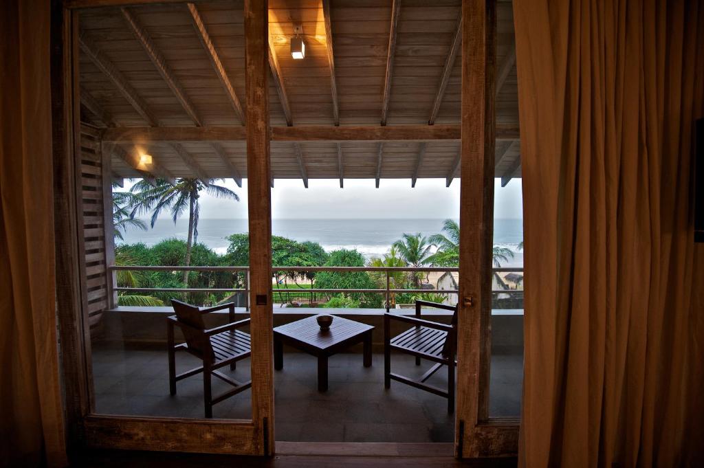 a room with a balcony with a table and chairs at Roman Beach Hotel in Hikkaduwa