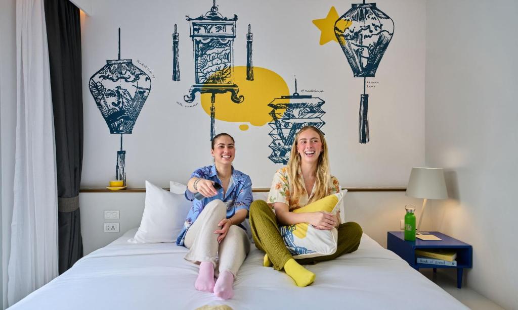 un uomo e una donna seduti su un letto di Lub d Phuket Patong - Near Patong Beach & Vibrant Social Vibe a Patong Beach