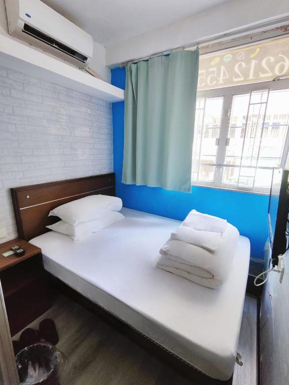 香港にあるTempo Inn West Kowloon HSR Stationの白いシーツと枕が備わるベッド1台が備わる客室です。