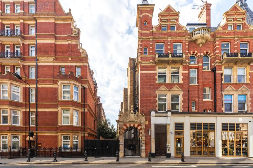 a large brick building next to two tall buildings at Kensington Luxury Suites in London