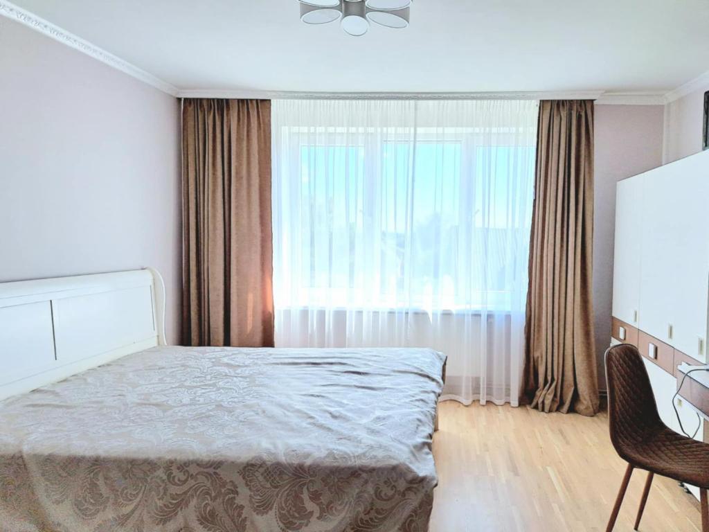 a bedroom with a bed and a large window at White Home & Garden in Klaipėda