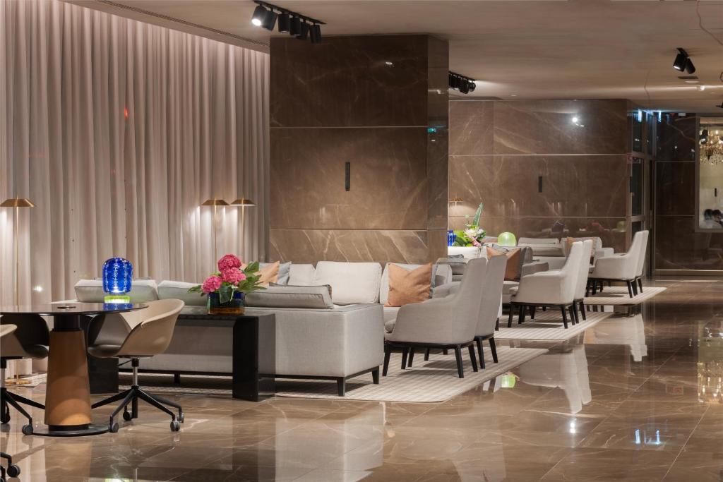 A polished hotel lounge with sofas, armchairs and small tables.
