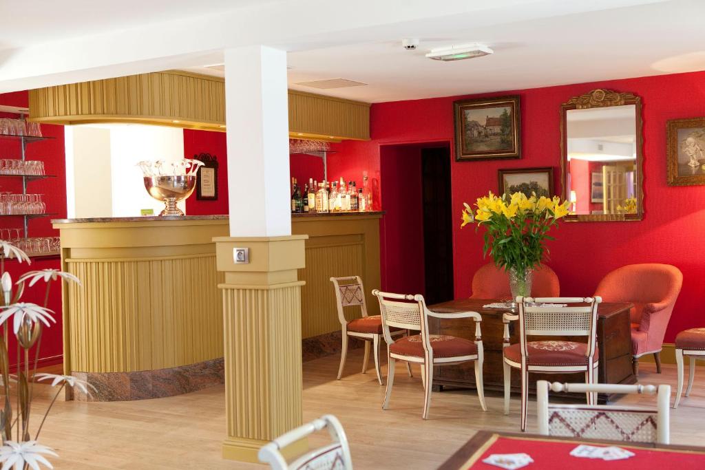 Oucques的住宿－Logis hôtel Ô en Couleur，一间拥有红色墙壁和桌椅的用餐室