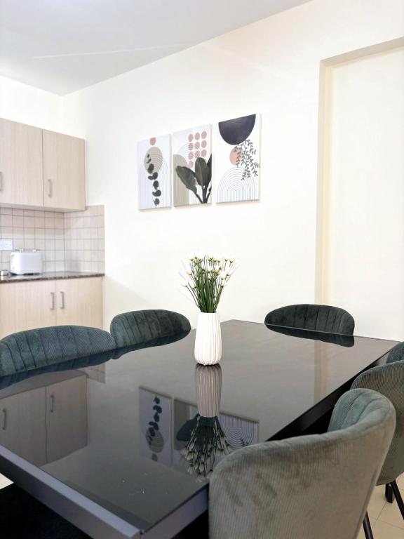 a dining room table with chairs and a vase of flowers at Sunrise Palette Suites in Larnaca