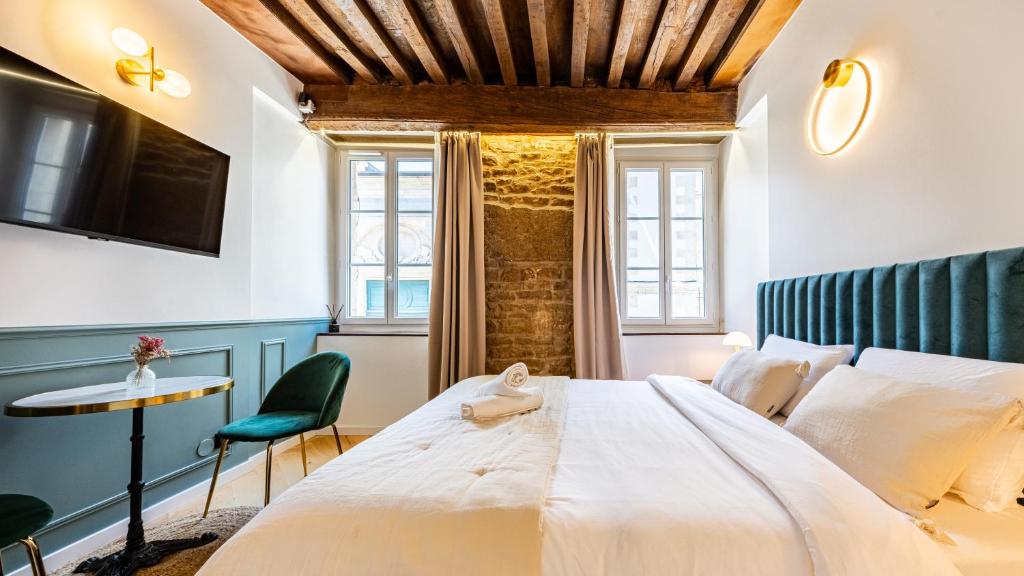 une chambre avec un grand lit blanc et une table dans l'établissement L'Écrin des Vignes - Appartement de Charme en Hyper-Centre, à Dijon