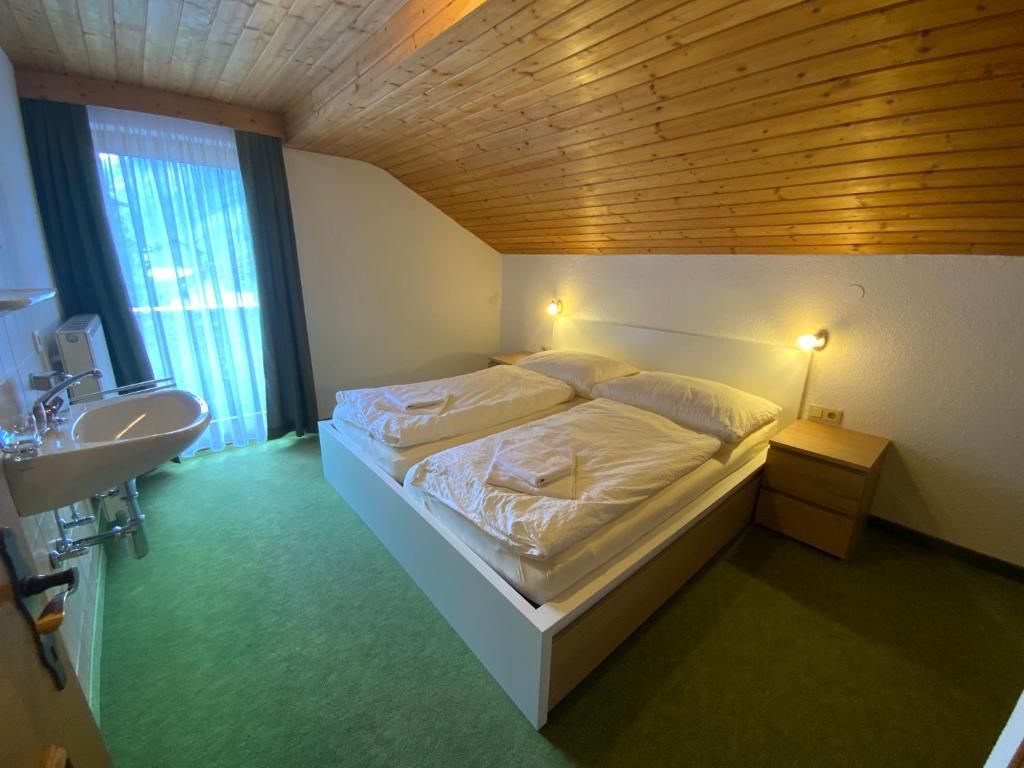 a bedroom with a white bed and a sink at Haus Praxmarer in Kaunertal