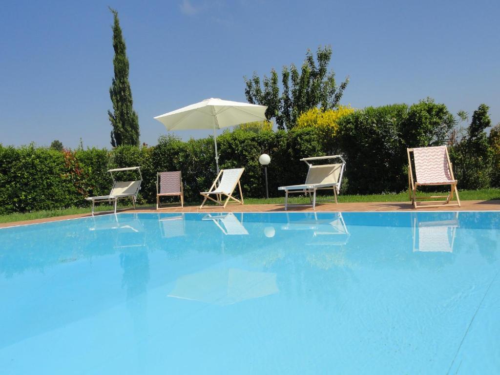 a group of chairs and an umbrella next to a swimming pool at Poggio Novello in Peccioli