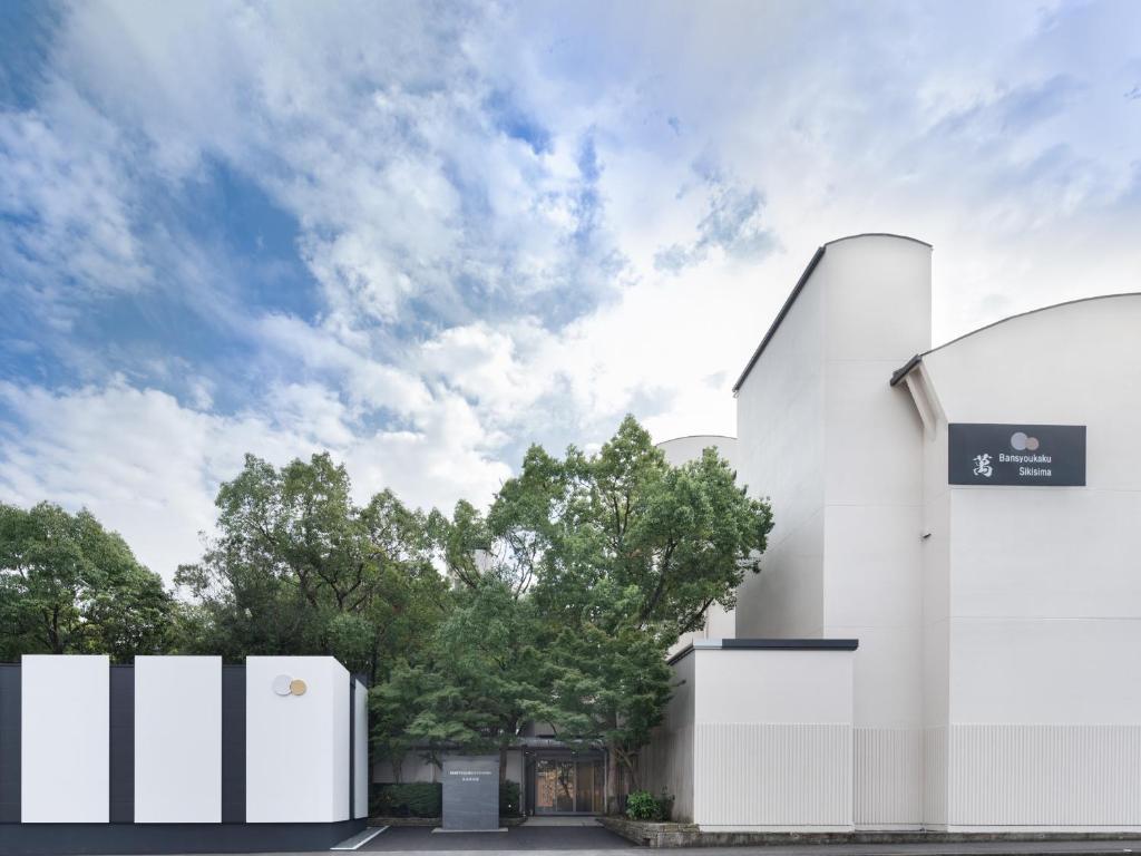a white building with a sign on the side of it at Bansyoukaku Shikishima in Ureshino