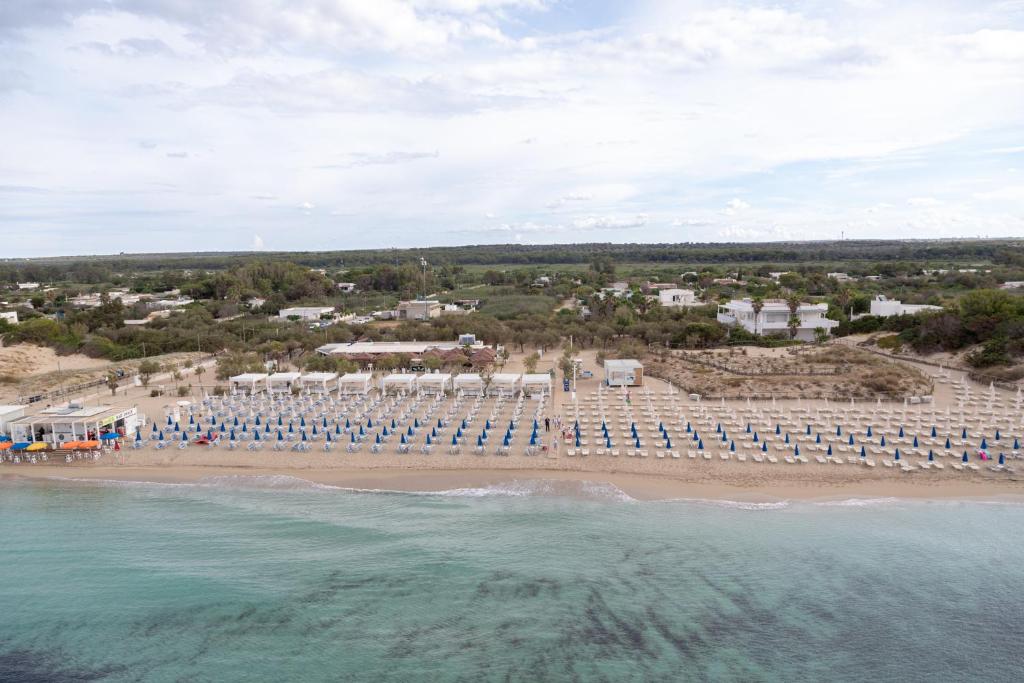 Lido degli Angeli Case Vacanza-Beach في بونتا بروسسيوتو: اطلالة جوية على شاطئ به كراسي و المحيط