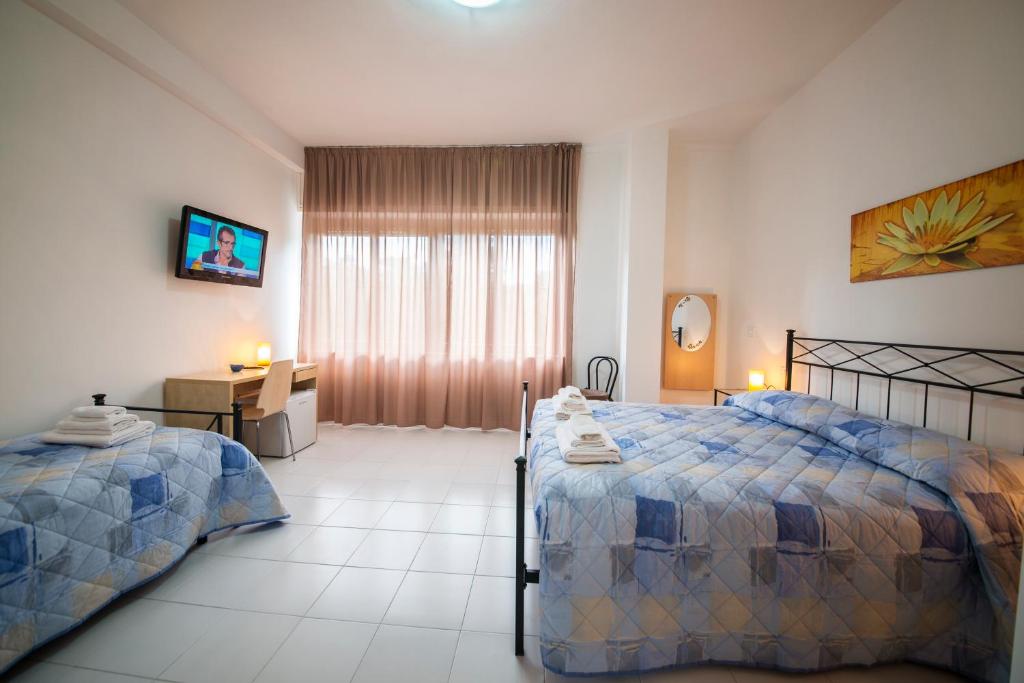 ein Schlafzimmer mit zwei Betten und einem Schreibtisch und einem Fenster in der Unterkunft Camere Oberdan in Foligno