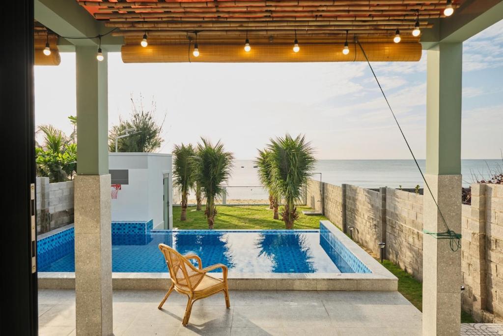 a patio with a pool and a chair and the ocean at Sea Sand Garden Villa in Phan Thiet