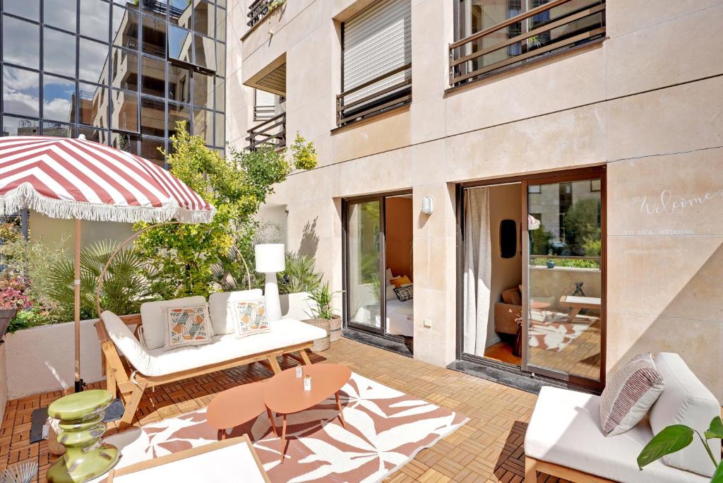 un patio avec une table, des chaises et un parasol dans l'établissement Appartement proche hôpital américain, à Levallois-Perret