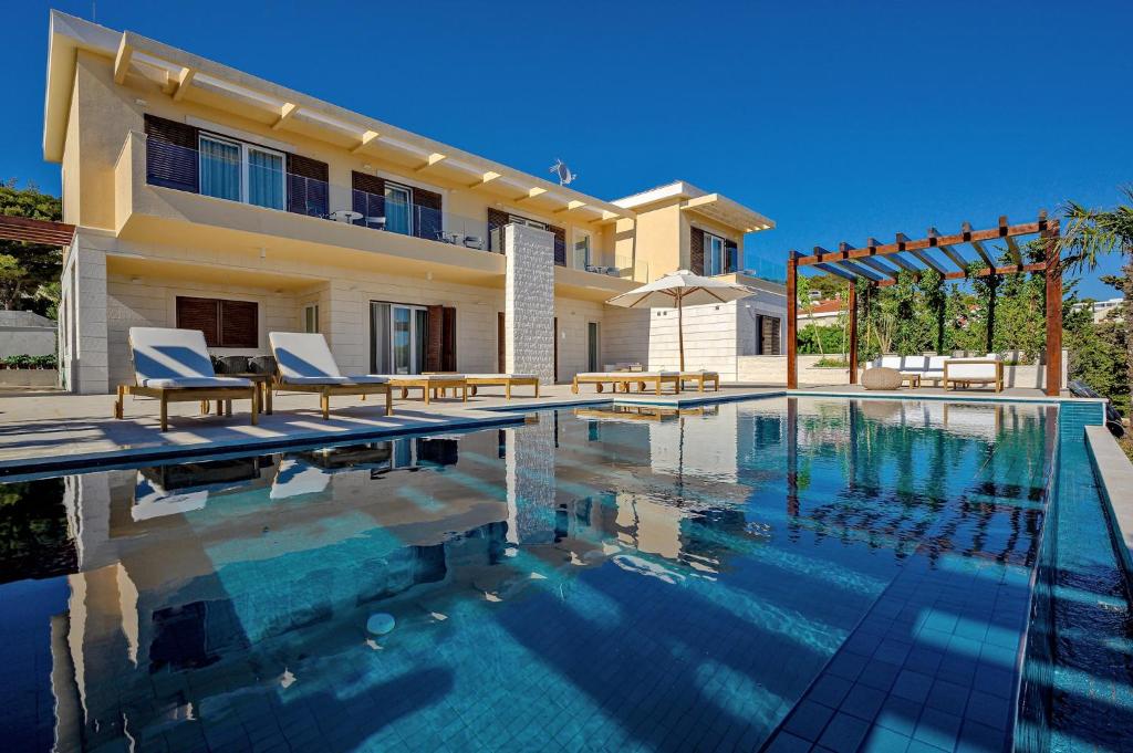 a villa with a swimming pool in front of a house at Immensely Luxurious Hvar Villa 5 Bedrooms Villa East Eternal Exceptional Sea Views & Private Pool in Hvar