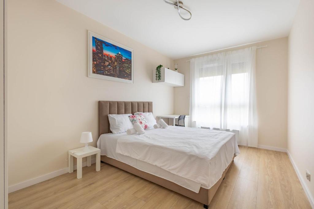 a white bedroom with a bed and a window at Miedza Apartament - Targówek, Metro Trocka in Warsaw