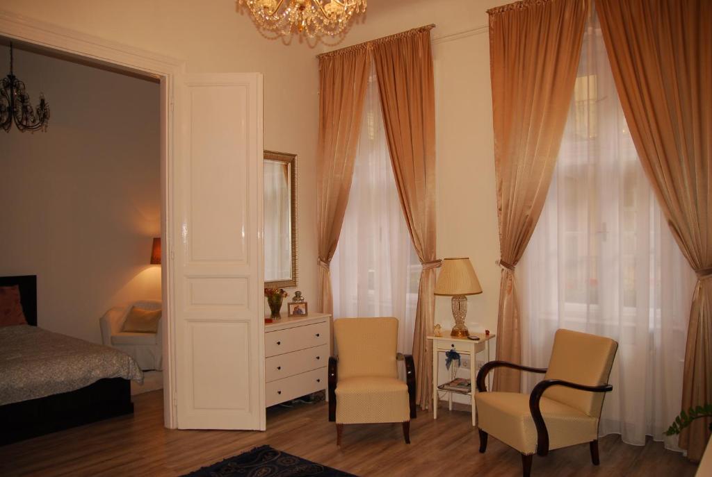 ブダペストにあるBalázs Apartment - Oktogonのベッドルーム1室(ベッド1台、椅子2脚、シャンデリア付)