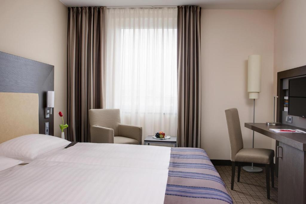 a hotel room with a bed and a desk and a window at IntercityHotel Bonn in Bonn
