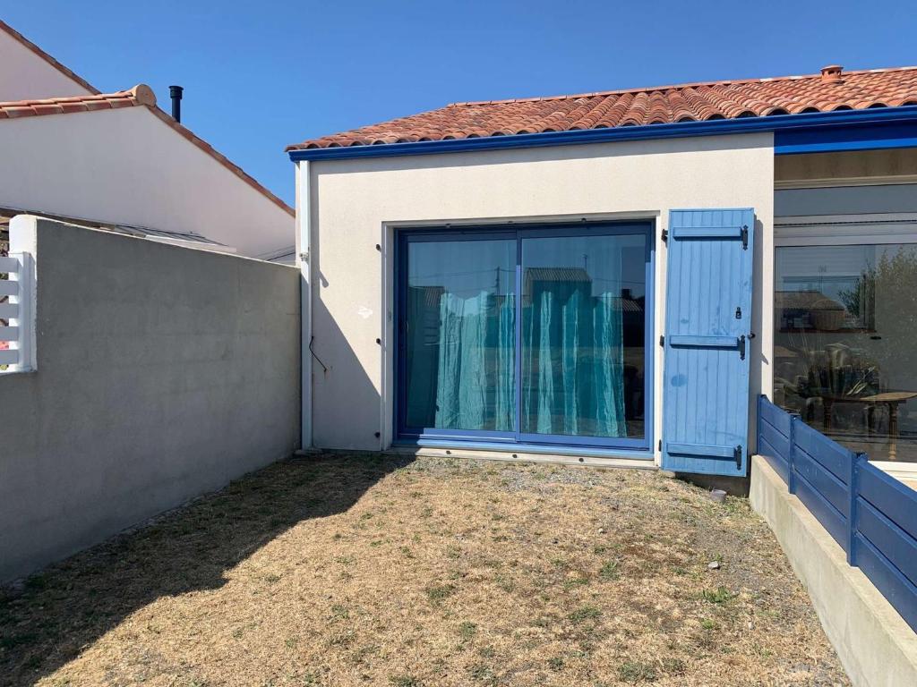 a house with a blue door and a patio at La Grisot de la mer Saint Hilaire in Saint-Hilaire-de-Riez