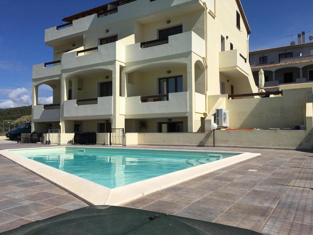 un immeuble avec une piscine devant un immeuble dans l'établissement Castelsardo Romantica, à Castelsardo