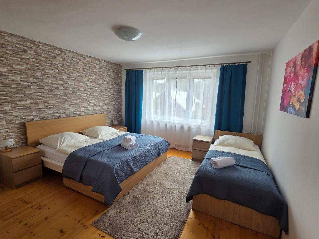 a bedroom with two beds and a brick wall at Apartmány 105 in Habovka