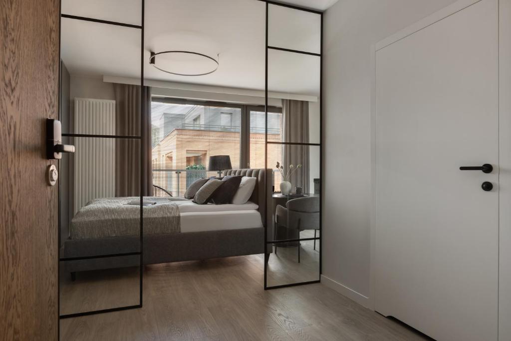 a bedroom with a bed and a glass door at Scala Apartamenty by Moderna Profit- Łąkowa 60E in Gdańsk