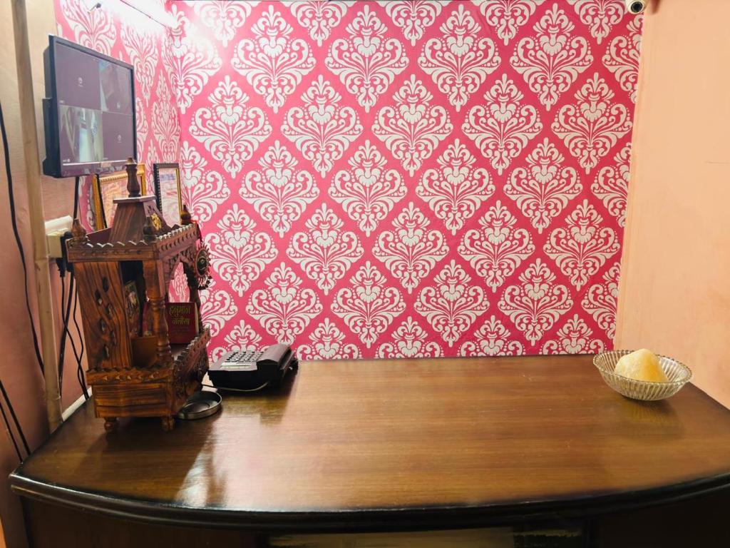 a room with a wooden table with a red wall at Ram ji guest house in Parwanoo