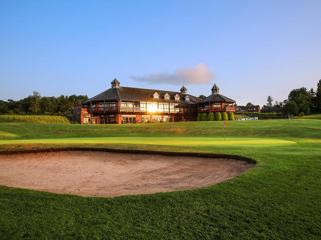 uma vista para um campo de golfe com um grande edifício em Macdonald Portal Hotel, Golf & Spa Cobblers Cross, Cheshire em Tarporley