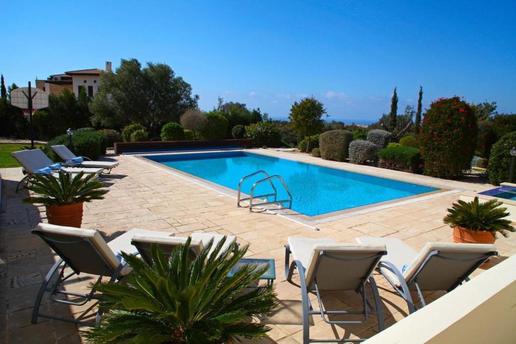 una piscina con sedie a sdraio e una piscina di Aphrodite Hills Superior Villas Superior Villa 0403 Air Conditioning 5 Bedrooms Paphos a Paphos