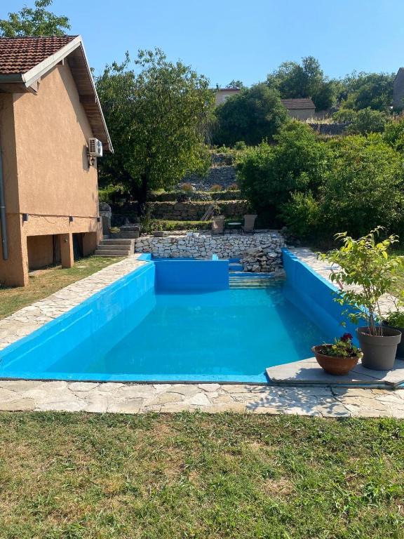a blue swimming pool in the yard of a house at Casa Madre Kravice Waterfalls in Ljubuški