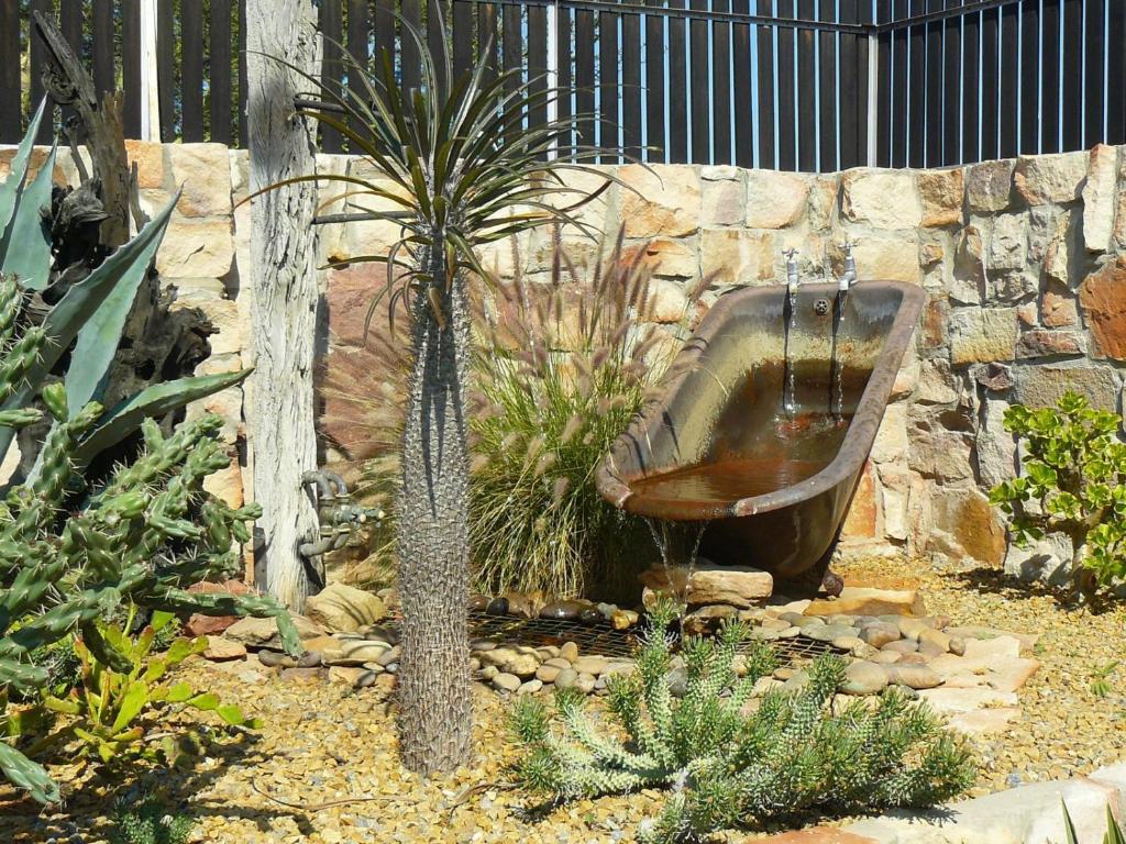 a garden with an old toilet in a stone wall at Klawer Hotel in Klawer