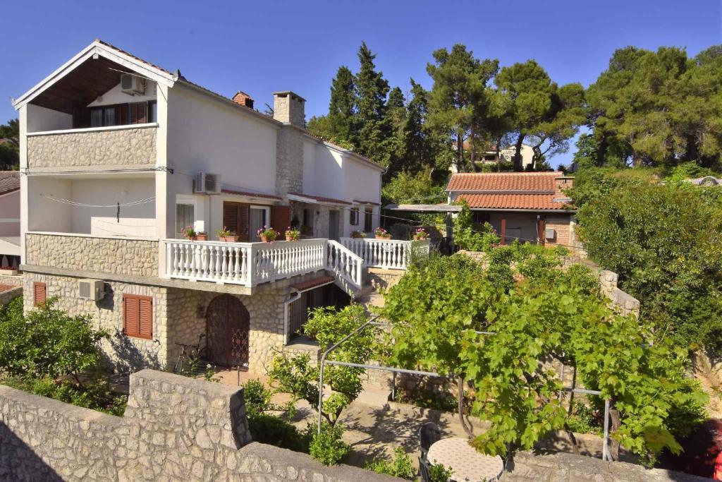ein großes weißes Haus mit Balkonen und Bäumen in der Unterkunft Apartments in Mali Losinj 14985 in Mali Lošinj