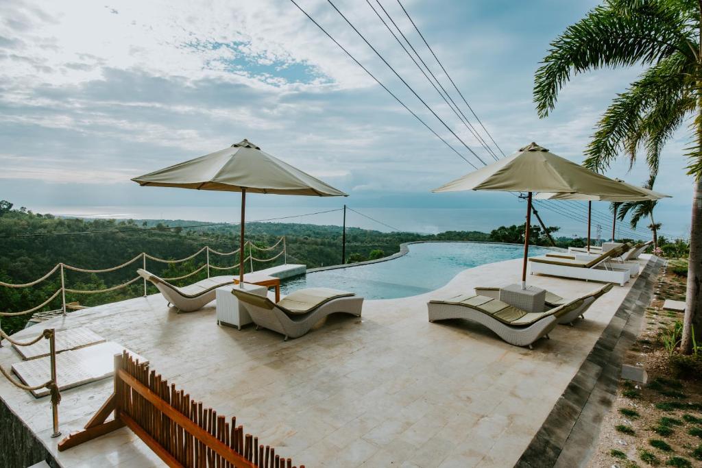 a pool with chairs and umbrellas on a patio at Samplangan Penida Resort in Nusa Penida