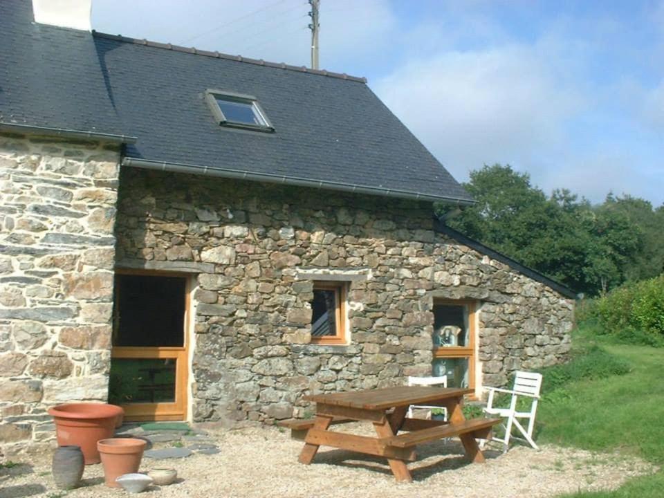 a stone building with a picnic table in front of it at maisonette mitoyenne in Lopérec