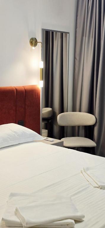 a bedroom with a bed and two chairs and a lamp at Naya Hotel in Almaty