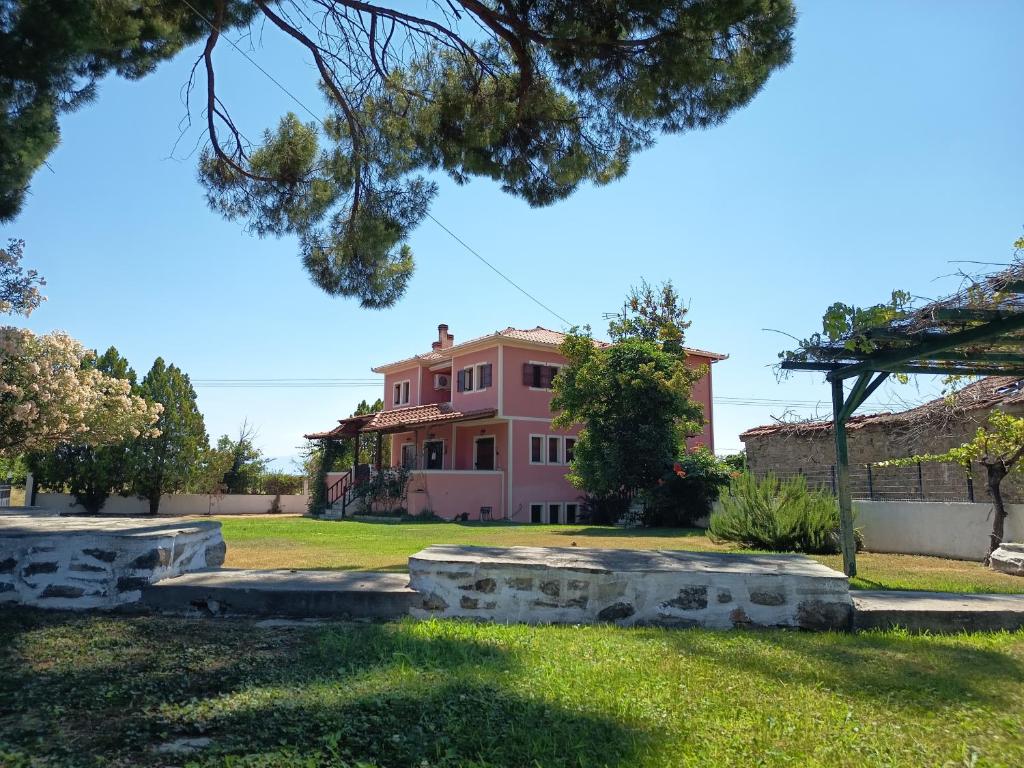 ein rosa Haus mit Felsen vor einem Hof in der Unterkunft Villa Lechonia in Káto Lekhónia